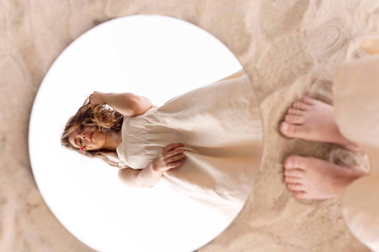 A round shaped mirror on sand glass with a girl's reflection