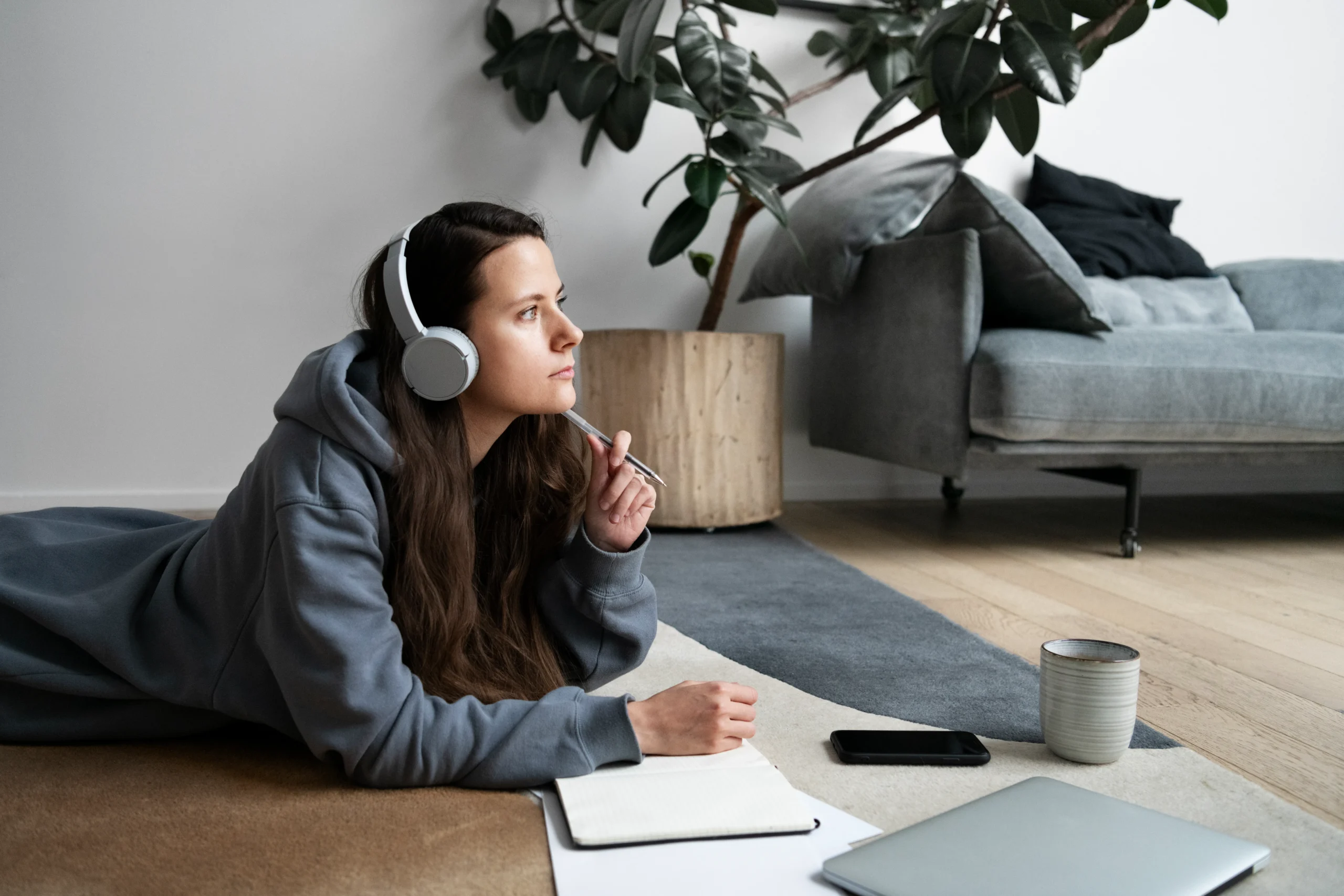 Person reading a book with headphones near a window